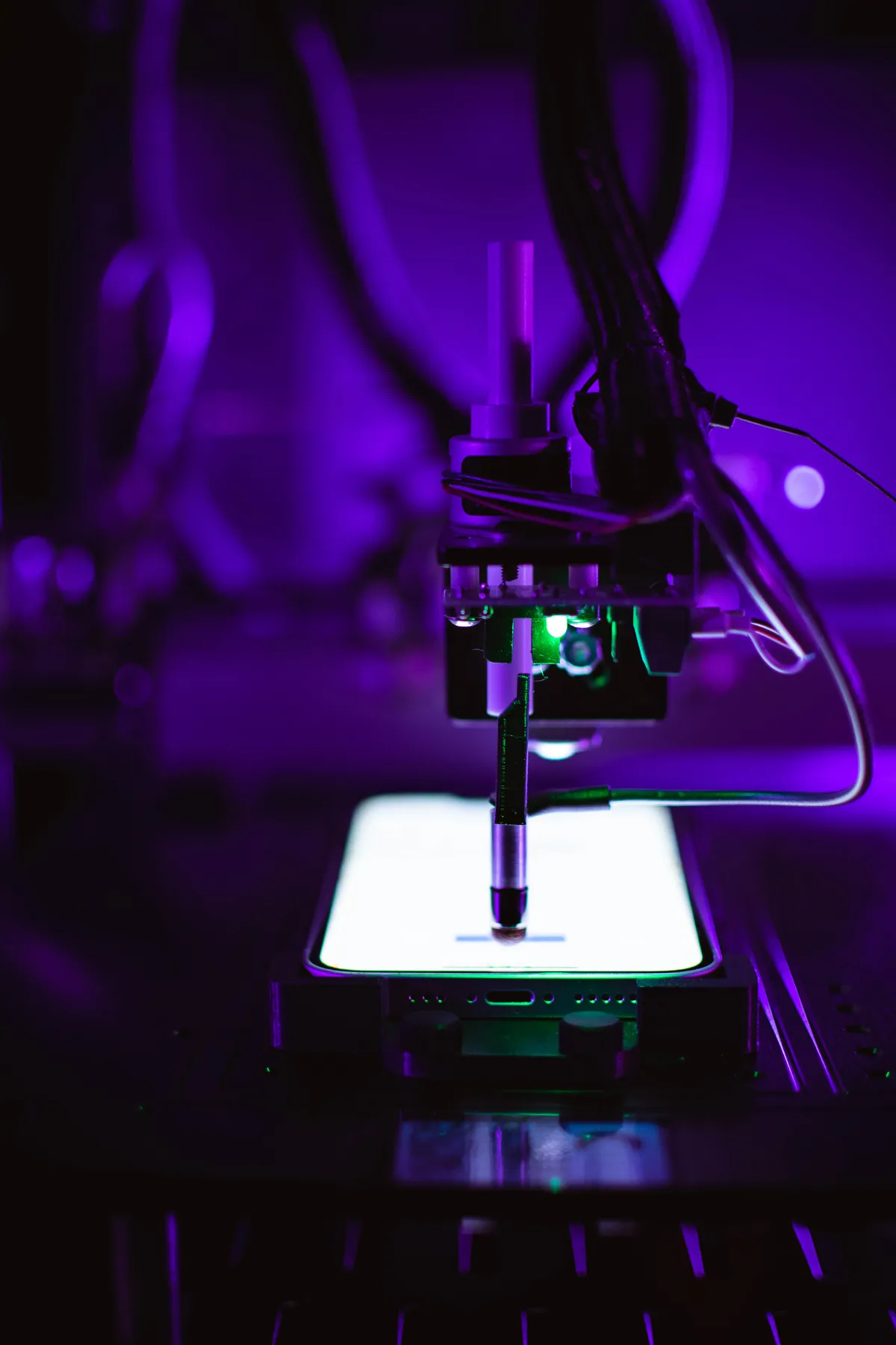 A robot stylus tapping the lit screen of a phone
