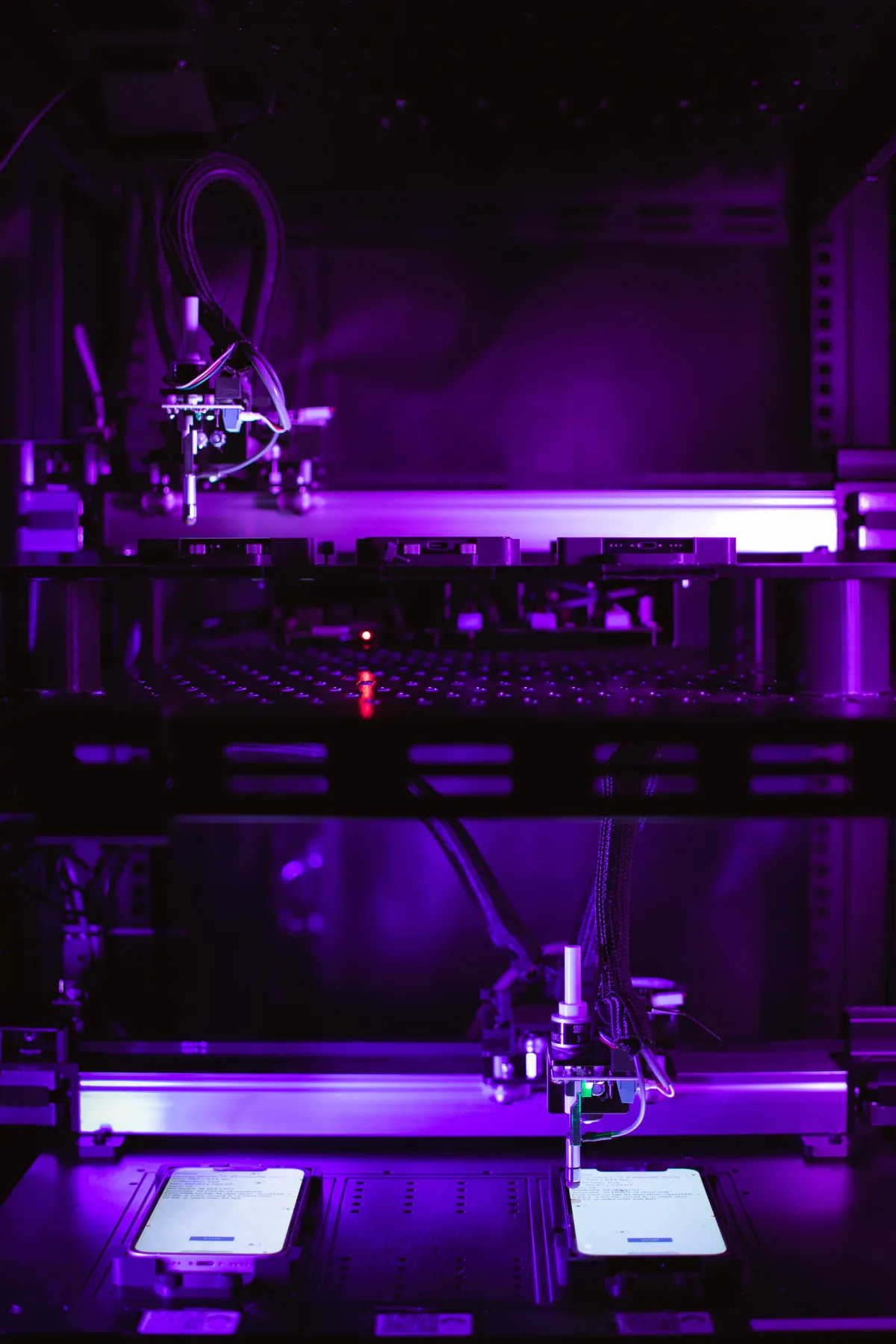 A two-tier robot rack, each tier holding phones on illuminated stages
